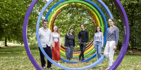 Das Bild zeigt die Mitarbeitenden vor den bunten Ringen vor grünen Bäumen: Sommer, Wilberg, Torney, Sebastian, Herms, v. Querfurth (von links nach rechts)