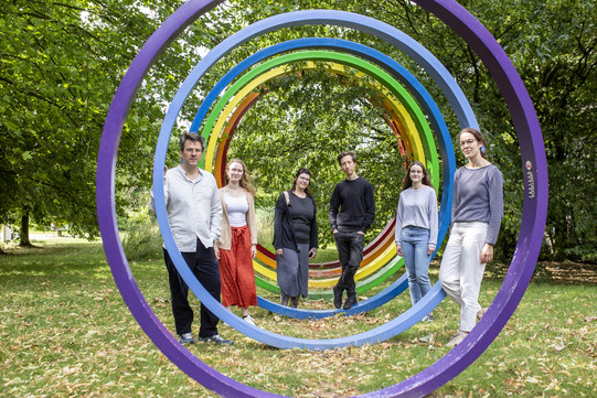 Das Bild zeigt die Mitarbeitenden vor den bunten Ringen vor grünen Bäumen: Sommer, Wilberg, Torney, Sebastian, Herms, v. Querfurth (von links nach rechts)