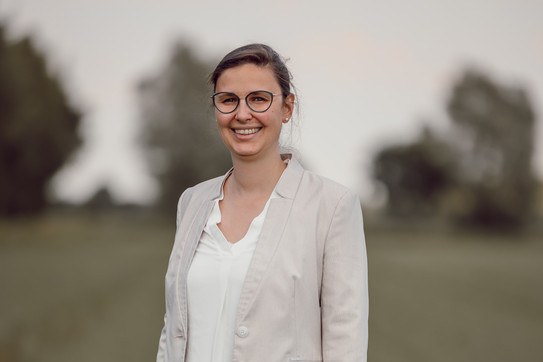 Kerrin Langer vor unscharfem Hintergrund, wie sie in die Kamera lacht.