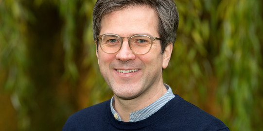 Portraitbild Bernd Sommer für grünem Hintergrund. Er lächelt und es sind Blätter zu erkennen.